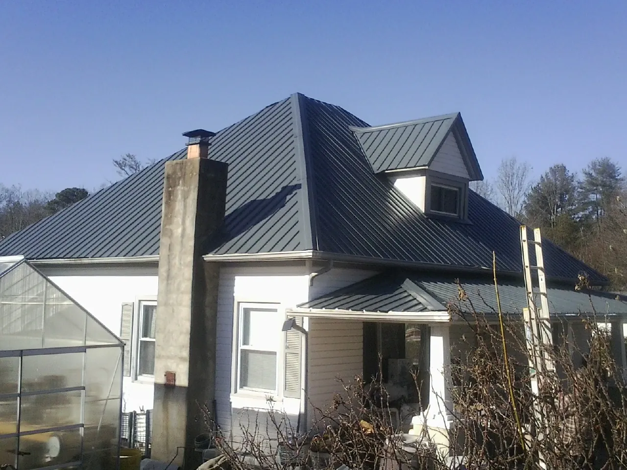 Dark blue standing seam metal roof on a white farmhouse with dormer — Slate & Tile Roof Repair by Roofing Brothers in Edwall