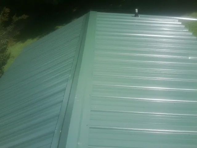 New green metal panels meeting at the ridge of a roof — Flat Roof Repair work by our crew in Edwall