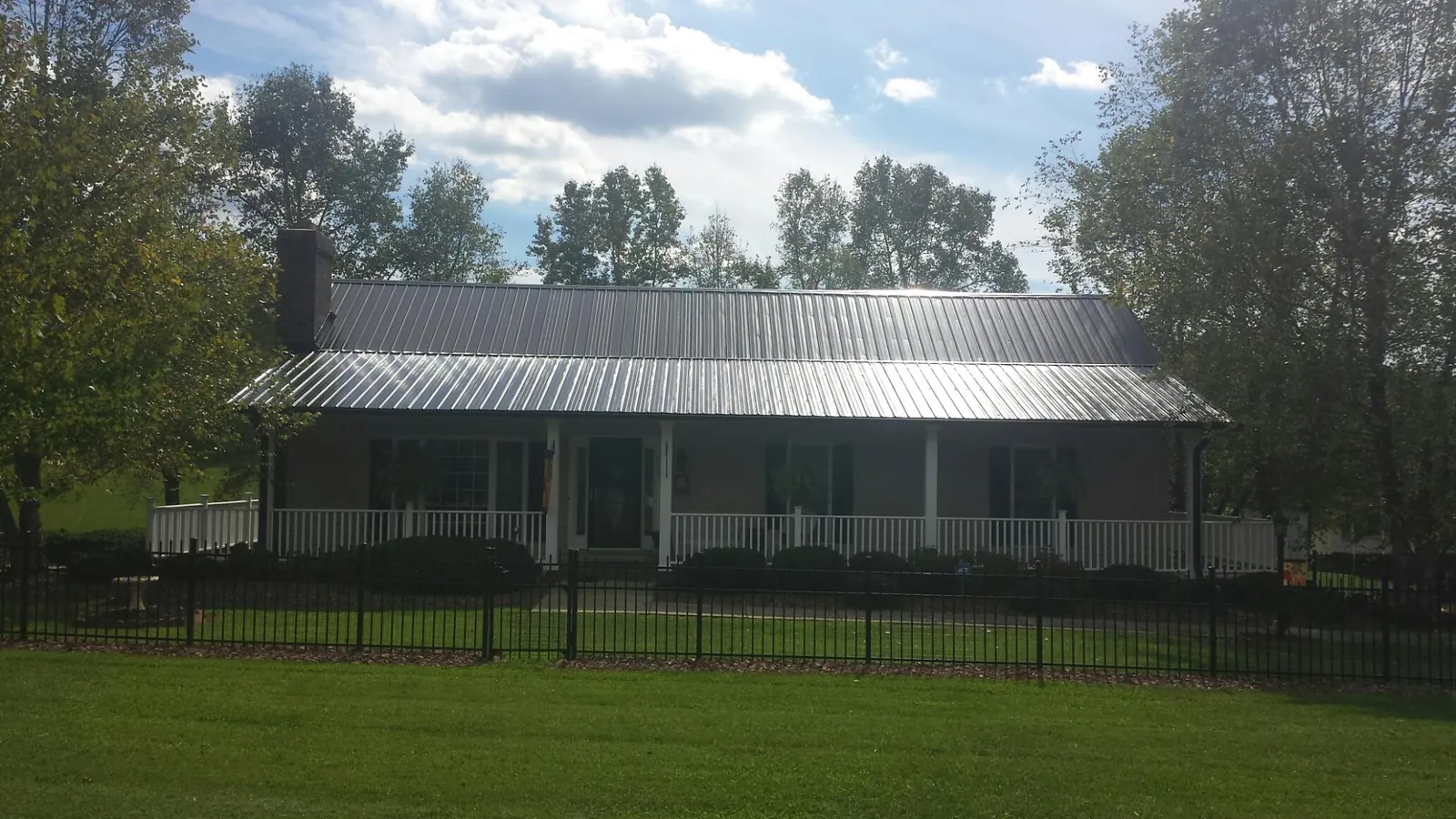 Gray metal roof on a brick ranch with a full width front porch — Gutter Guard Installation work by our crew in Edwall