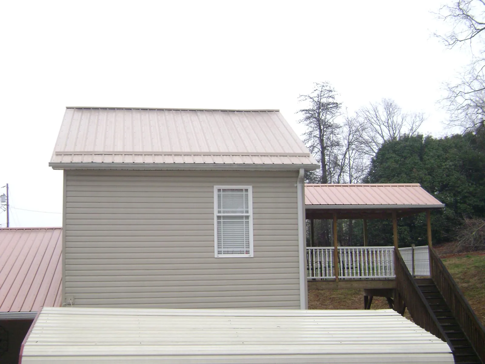 Tan metal roofs on a two story addition and attached porch, from a Roof Replacement job in Edwall