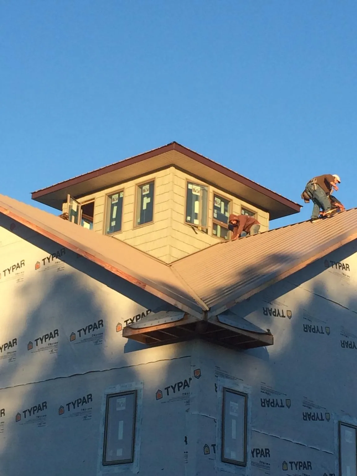 Roofers working around a rooftop cupola on a new metal roof at sunset — Roof Waterproofing in Edwall by Roofing Brothers